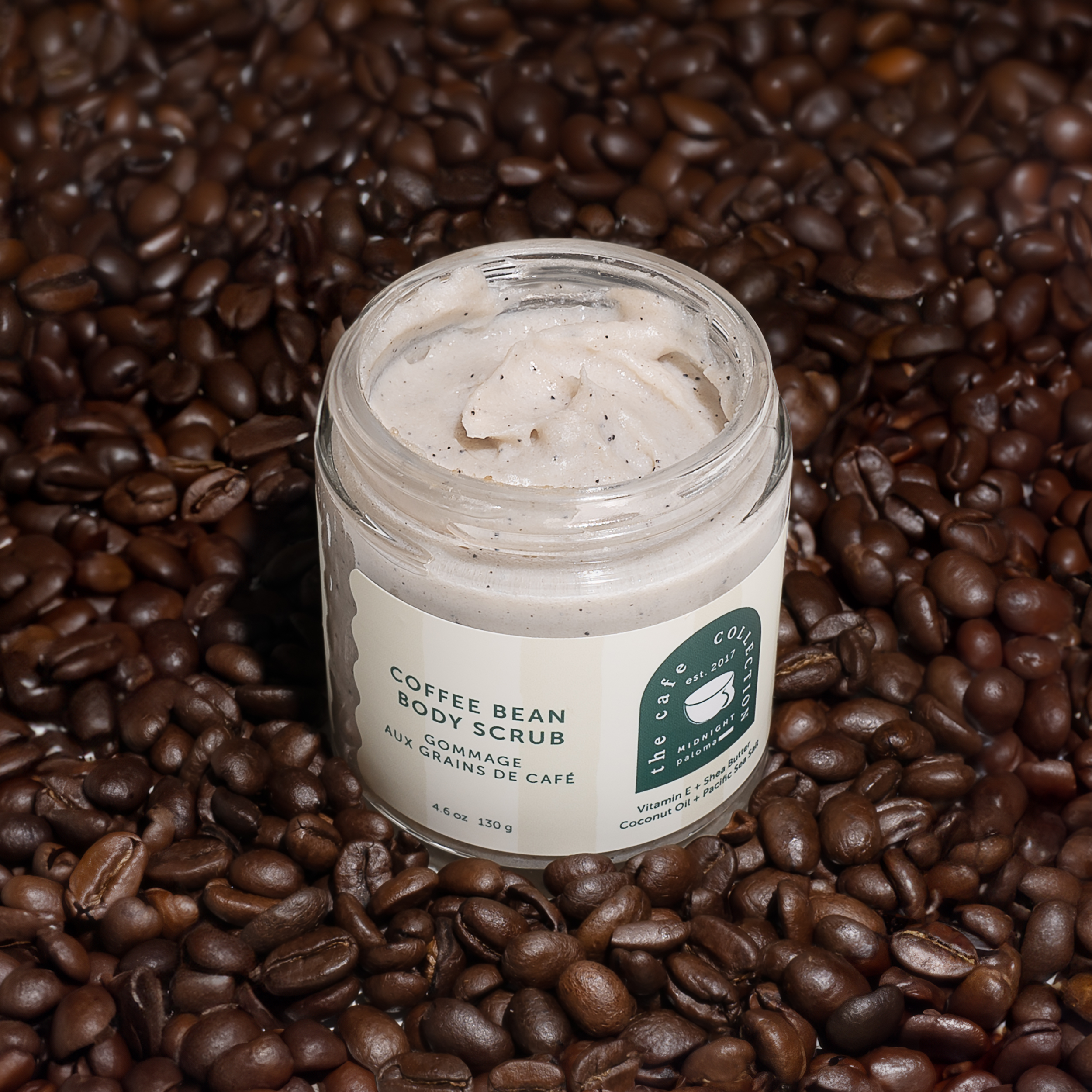 Danielle Gracioso Graphic Designer Vancouver BC Canada – Open jar of Coffee Bean Body Scrub by Midnight Paloma, surrounded by whole coffee beans. Label designed by Danielle Gracioso.