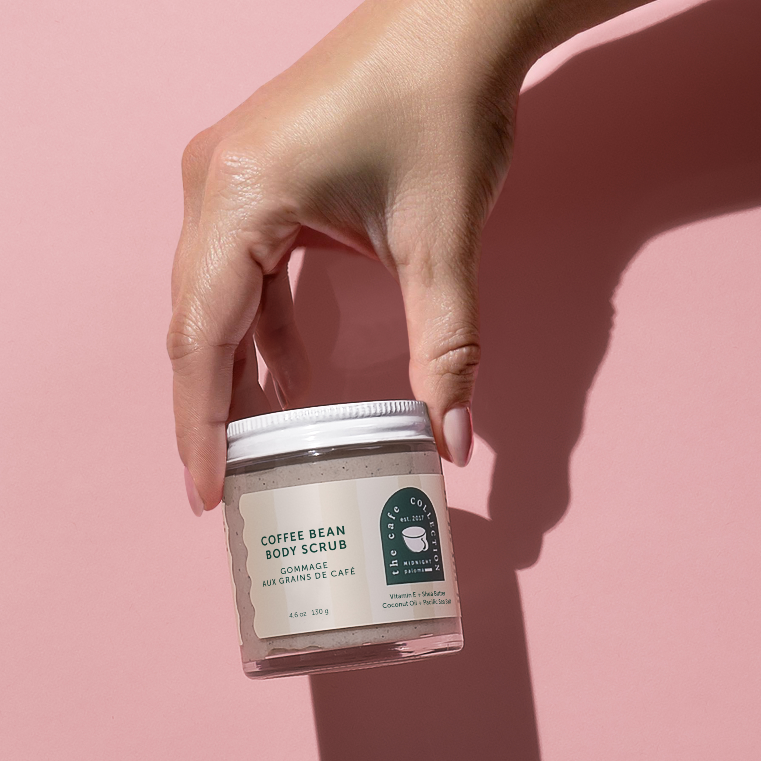 Danielle Gracioso Graphic Designer Vancouver BC Canada – Hand holding Midnight Paloma’s Coffee Bean Body Scrub against a soft pink background. Clean, minimalist packaging designed by Danielle Gracioso.