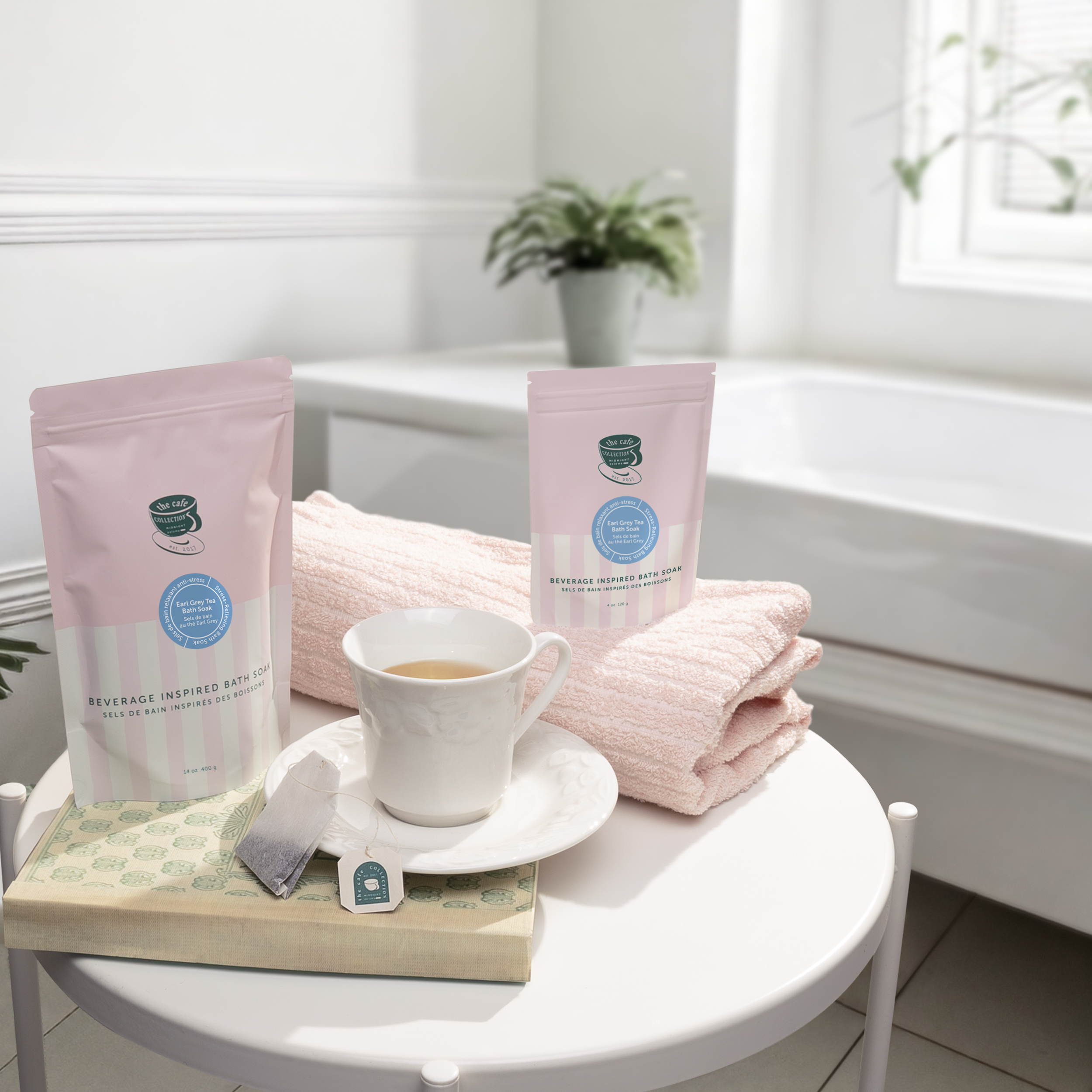 Danielle Gracioso Graphic Designer Vancouver BC Canada – Earl Grey Tea Bath Soak in two pouch sizes styled on a side table with a tea cup, pink towel, and plant in the background. Art direction and photography by Danielle Gracioso.